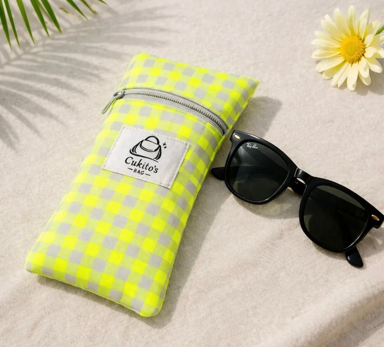 Funda porta móvil de Cukito's Bag junto a unas gafas de sol